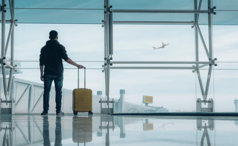 Person stood alone in empty airport with suitcase