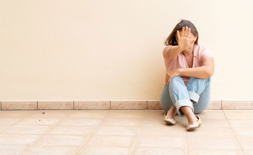 Woman sitting holding out hand defensively 